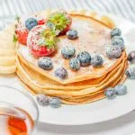 Image du Pancakes moelleux garnis de fruits frais, parfaits pour le petit-déjeuner.