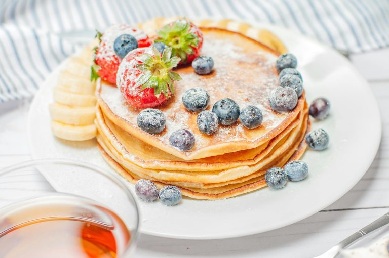 Image du Pancakes moelleux garnis de fruits frais, parfaits pour le petit-déjeuner.