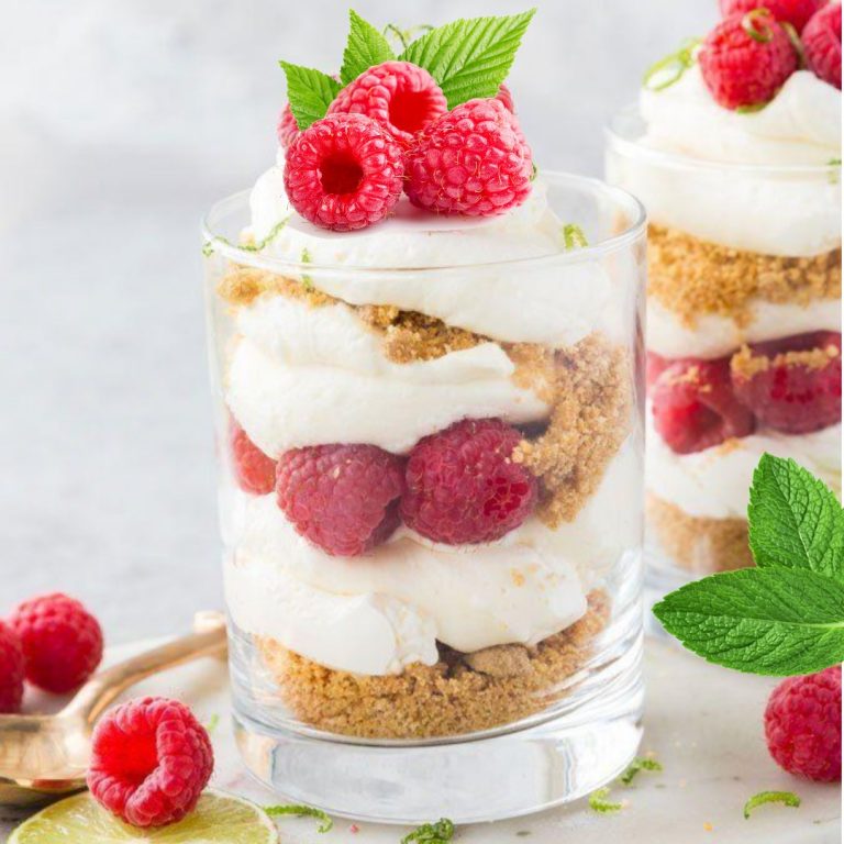 Image d'un verre de Verrine aux framboises fraîches, garnie de crème légère et de fruits rouges.