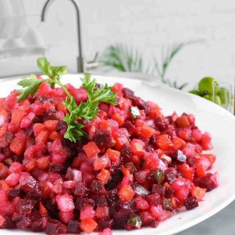 Image d'une salade russe avec betterave, un mélange de légumes colorés et une sauce crémeuse.